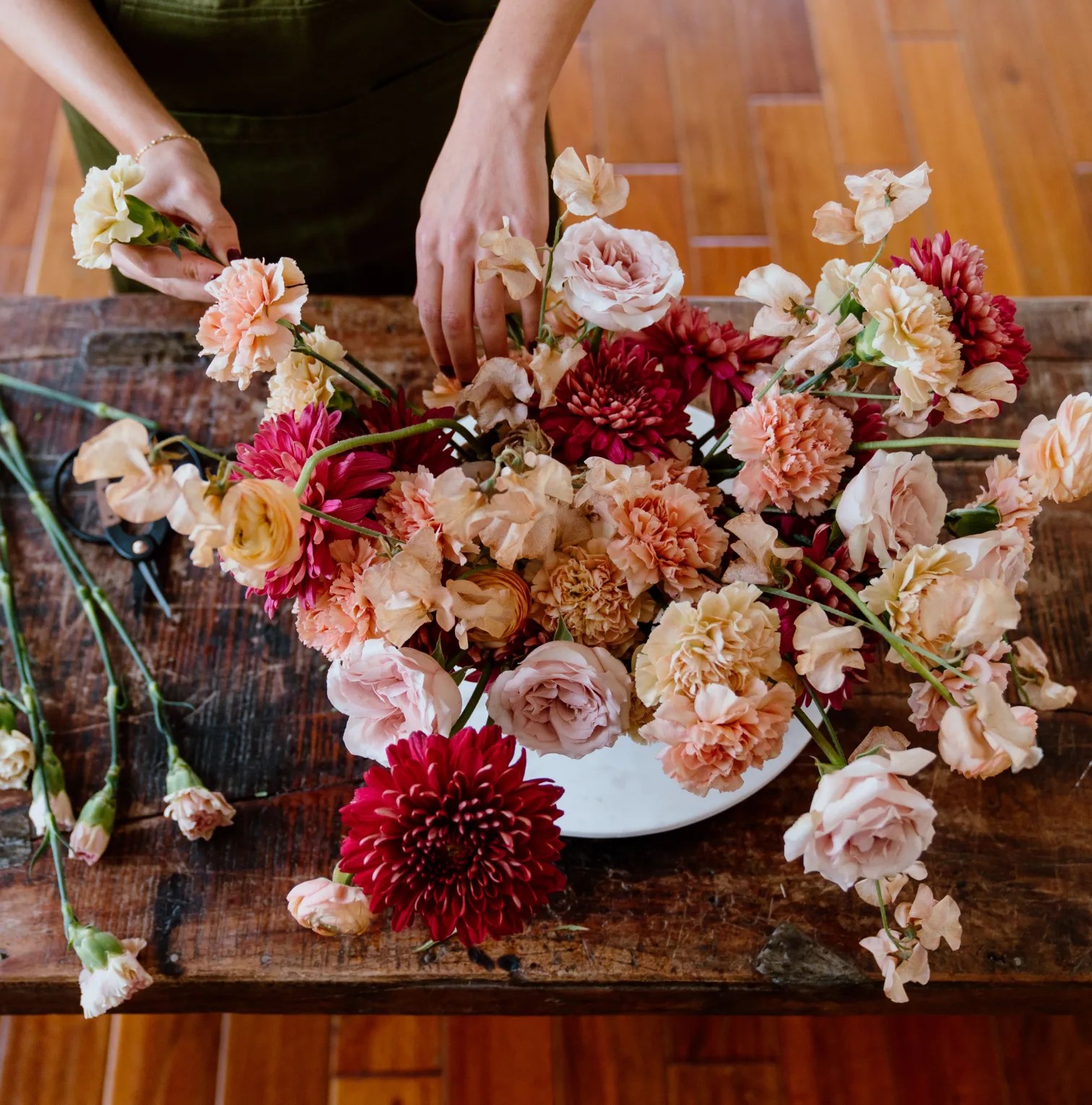 a woman arranging flowers on a wooden table