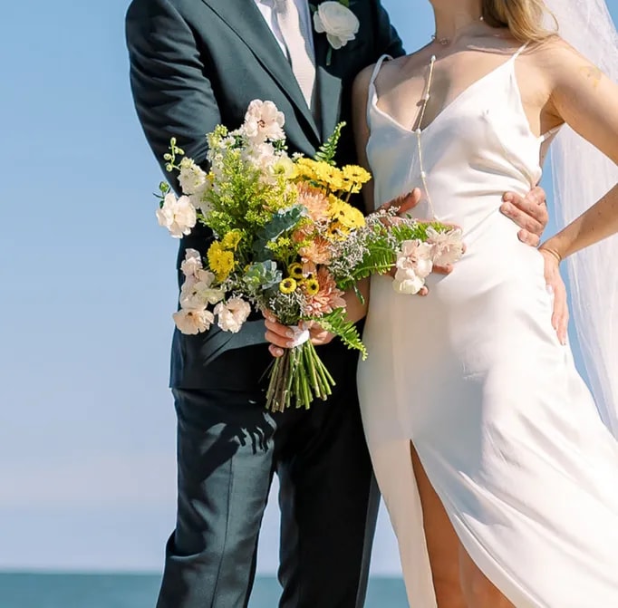 Couple holding a yellow wildflower-inspired bouquet